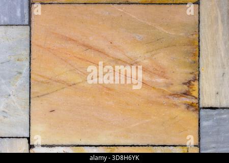 Close-up of a single aged and textured marble floor tile in warm beige and light brown tones with subtle dark veining, showing signs of wear and time. Stock Photo