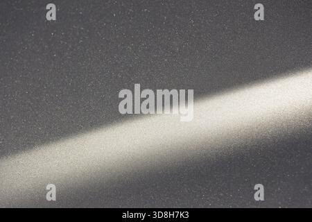 Calm abstract background with diagonal ray of light shining on dark, textured gray surface. This quiet interplay of shadow and illumination creates ho Stock Photo