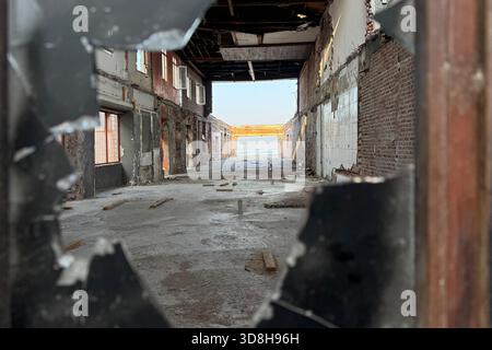 Empty ruins of a very heavily polluted industrial factory, abandoned empty building through burned black broken shattered glass, red stone tile wall Stock Photo