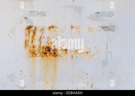 A close-up shows a worn white painted metal surface with orange-brown rust where paint has chipped. Faint outlines and adhesive marks suggest removed stickers. Stock Photo