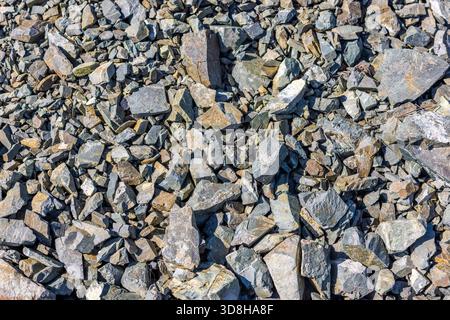 Pile of various gray and brown natural rocks and stones under bright sunlight - full-frame background, quarry material or construction aggregate. Stock Photo