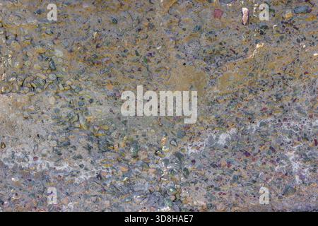 Close-up of a rough, uneven concrete surface embedded with small pebbles and showing signs of age and wear. Stock Photo