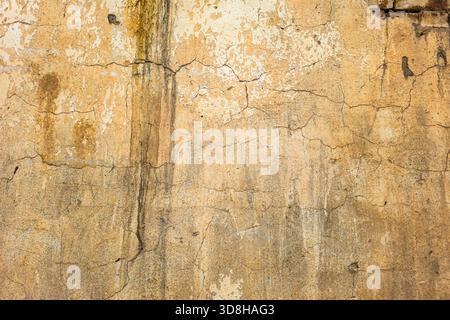 A close-up shot shows an aged beige stucco wall with a weathered surface. The grunge background reveals cracked plaster and a distressed finish, creating a textured appearance. Stock Photo