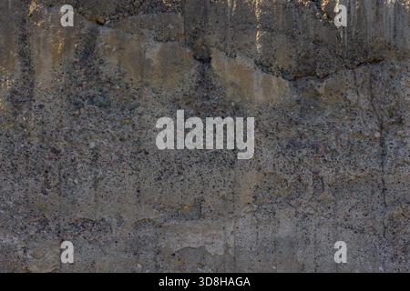 Close-up of a rough, weathered, and cracked concrete wall surface showing detailed texture, aggregate, and signs of aging and decay. Stock Photo