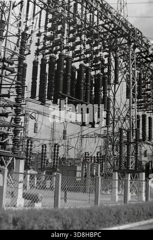 Donetsk region, Ukrainian SSR, Soviet Union. 1970s. A complex industrial view of the Open Switchgear (OSG) at a high-voltage electrical substation. Massive arrays of dark porcelain suspension insulators and heavy line equipment hang from a metal portal structure. Behind a wire mesh fence, a dense network of busbars, disconnectors, and transformers forms the backbone of the energy grid. A symbol of Soviet electrification power. Life in peaceful Donbas before the war. Stock Photo