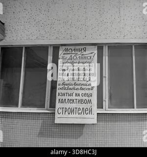 Donetsk region, Ukrainian SSR, Soviet Union. 1970s. A critical "Molniya" (Lightning) wall newspaper poster on the window of the administration building at the "Donbasskaya" 750 kV substation construction site. The handwritten text publicly criticizes "Comrade Dolina" for delaying equipment delivery, disrupting the commissioning schedule and the builders' commitments. A unique document of Soviet industrial relations and planned economy problems. Life in peaceful Donbas before the war. Stock Photo
