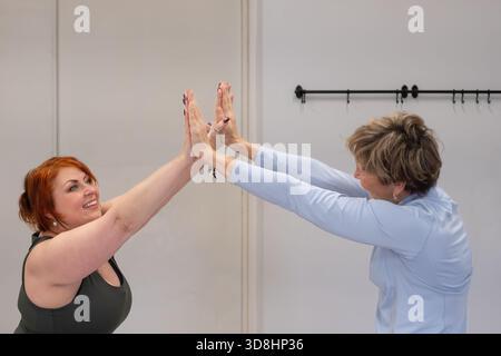 Women are joyfully practicing yoga together in a bright studio, highlighting the essence of connection and mindfulness Stock Photo