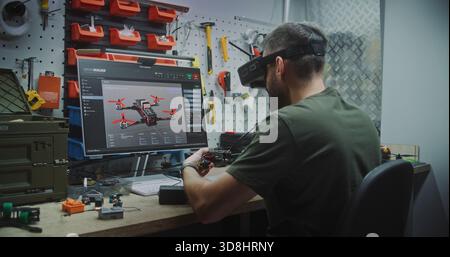 Man Designing and Assembling Drones. Engineer Wearing FPV Goggles Simultaneously Designing Drone on Screen and Assembling Workbench. Concept of Advanced Research and Development in Drone Technology. Stock Photo