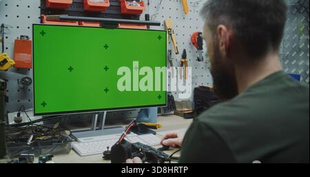 Engineer Working on Drone With Chromakey Placeholder Display. Green Screen Monitor With Tracking Markers Visible of Engineer Assembling Drone. Custom Software, Data, or Virtual Reality Interfaces. Stock Photo