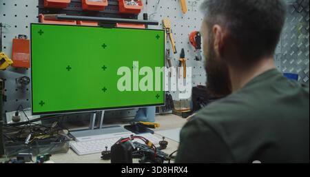 Engineer Working on Drone With Chromakey Placeholder Display. Green Screen Monitor With Tracking Markers Visible of Engineer Assembling Drone. Custom Software, Data, or Virtual Reality Interfaces. Stock Photo