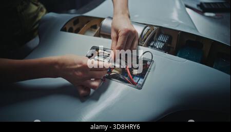 Close Up Worker Hand Assembling Critical Electronic Modules Into Next Generation Drone. It Represents Precision Manufacturing and Sophisticated Processes Involved in High Tech Defense Production. Stock Photo