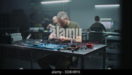 Man Assembling High Speed FPV Drone For Professional Use. Man Intensely Focused on Assembling High Speed FPV Drone, Working on Internal Wiring and Frame. Concept of Growing Field of FPV Technology. Stock Photo
