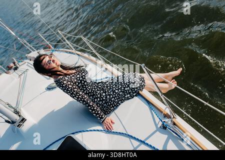 Woman in sunglasses enjoying sunbathing and relaxing on a sailboat by the sea Stock Photo