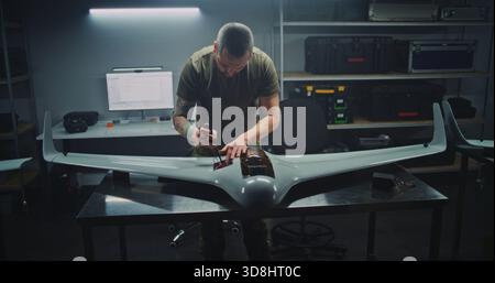 Woman and Two Men Collaboratively Assemble Unmanned Aerial Vehicle in Secure, Well Organized Workshop. Concept of Gender Diversity and Focused Teamwork in High Stakes Technology Defense Production. Stock Photo