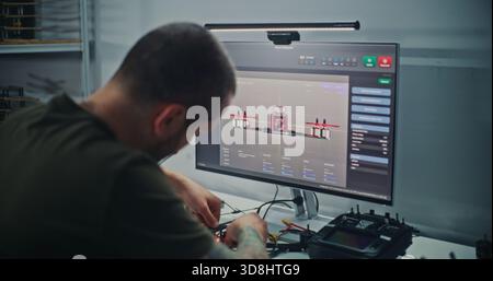 Male Engineer With Visible Tattoos Sits at Computer, Designing FPV Drone Model Using Specialized 3D Software For Drone Testing. Concept Technical Process Product Development and Digital Engineering. Stock Photo