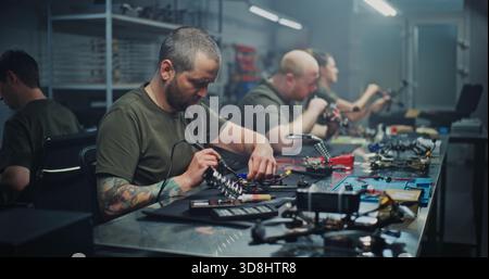 Diverse Specialists, Including Men and Women, Perform Various Tasks Like Soldering and Computer Design in High Tech Workshop. Concept of Specialized Roles and Gender Diversity in Drone Development. Stock Photo