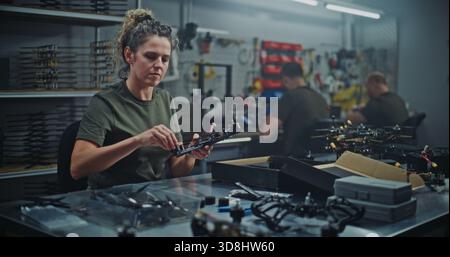 Female Technician Engaged in Hands on Assembly of Modern FPV Quadcopter, Connecting Small Parts Frame. Concept Meticulous Production Process and Quality Control in Professional Tech Facility. Stock Photo