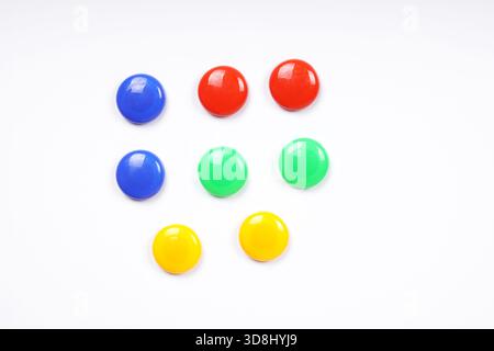 colorful round magnets in blue green red and yellow on white whiteboard background Stock Photo