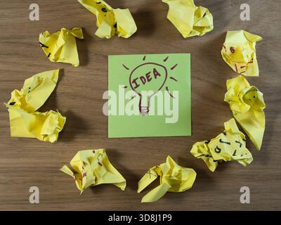 Brilliant Idea From Failed Attempts - Fresh idea on a green note among crumpled paper. Symbolizes brainstorming, problem-solving, and the creative pro Stock Photo