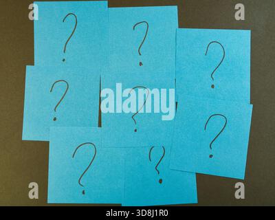 Blue Sticky Notes with Question Marks - Arrangement of blue sticky notes, each with a question mark, against a dark background. Ideal for concepts of Stock Photo