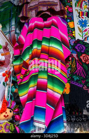 Colorful Woven Mexican Serape Hanging In A Market With Other Textiles Stock Photo
