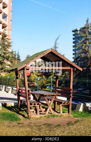 Rustic wooden gazebo and picnic table providing a spot for relaxation and outdoor activities in a city park Stock Photo