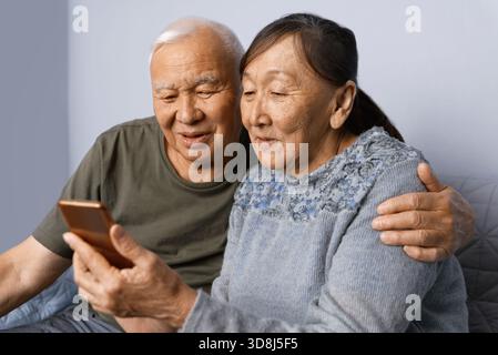 Senior couple at home using smartphone Stock Photo