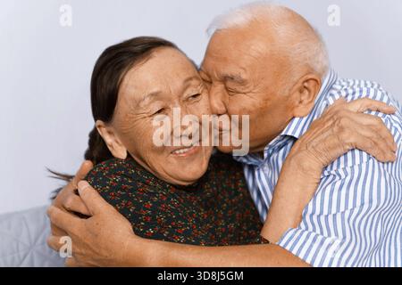 Senior man hugging and kissing his wife Stock Photo