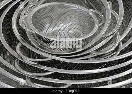 Group of round stainless steel collanders, various sizes, empty and clean, close-up shot, abstract background Stock Photo