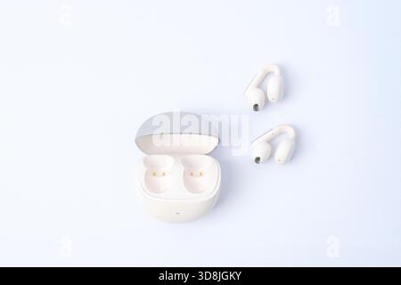 Wireless earbuds and open charging case on a bright minimal background. Top view. Stock Photo