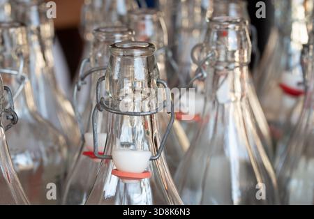 Many empty bottles stand next to each other. The glass bottles have ceramic, rubber and metal caps. The openings and necks of the bottles can be seen. Stock Photo