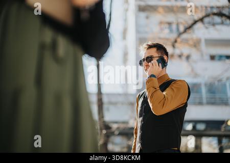 Smartly dressed man on phone in city street, stylish vest and sunglasses in daylight Stock Photo