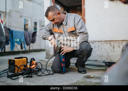 Construction worker using an angle grinder on an outdoor project with power tools and cables Stock Photo