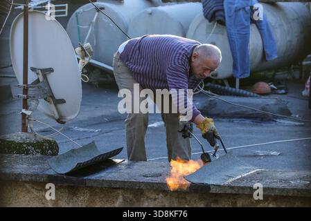 Tirana, Tirana, Albania. 1st Dec, 2025. A man placing a waterproof membrane on his roof to cover a spot where water is seeping in here in Tirana, Albania on 01 December 2025. A government draft decision proposed a technical audit for buildings over 50 years old to check their structural integrity. The stated goal was to assess the buildings condition and determine if they needed repair, demolition, or were already up to standard, not to demolish them all. (Credit Image: © Armando Babani/ZUMA Press Wire) EDITORIAL USAGE ONLY! Not for Commercial USAGE! Stock Photo