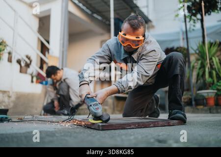 Construction worker using an angle grinder outdoors with safety goggles, sparks flying Stock Photo