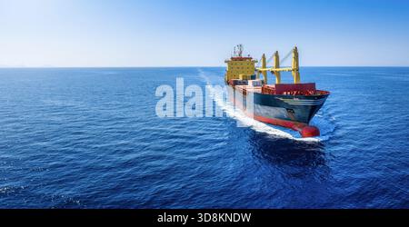 Aerial view of a universal bulk carrier cargo vessel traveling with high speed over blue sea with copy space Stock Photo