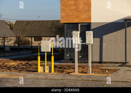 Exterior view of a newly built house with outdoor utility meters and yellow gas pipes installed. A suburban construction site is visible in the backgr Stock Photo