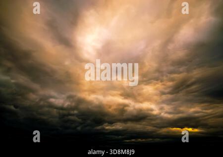 The ominous clouds create a moody atmosphere, with the sun breaking through the darkness Stock Photo