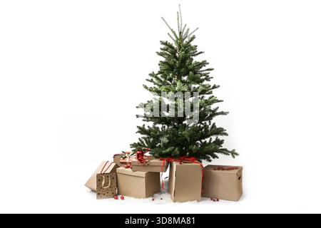 Preparation for Christmas, artificial fir tree without decorations, many cardboard boxes for gifts underneath ready to be wrapped, isolated on a white Stock Photo