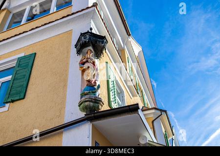 statue-mounted-on-exterior-wall-with-stained-glass-backdrop-stock-photo