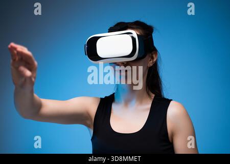 Woman using VR headset with outstretched arm inside immersive virtual reality digital environment Stock Photo