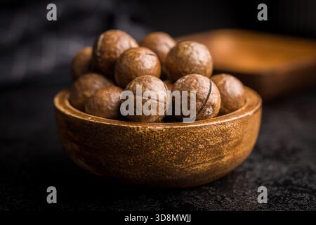 Tasty macadamia nuts in bowl on a black table. Stock Photo