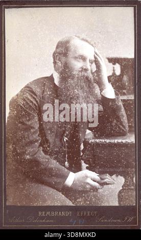 A sepia-toned studio portrait of a bearded man seated in a contemplative pose, resting his head on one hand and holding a small book. The mount reads “Rembrandt Effect” and credits Adams Bros., 127 New Bond Street, London. Ornate furniture appears in the background. From a late Victorian to early Edwardian original photograph album which featured many albumen cabinet cards and carte de visites, providing a window to the styles and fashions of the time. Stock Photo