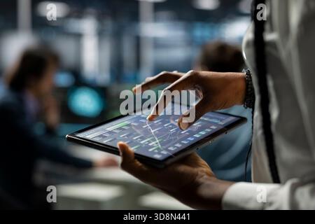 Close up of data center computer scientist using tablet, deploying servers and network hardware. IT specialist in server farm using device to manage large scale IT infrastructure Stock Photo
