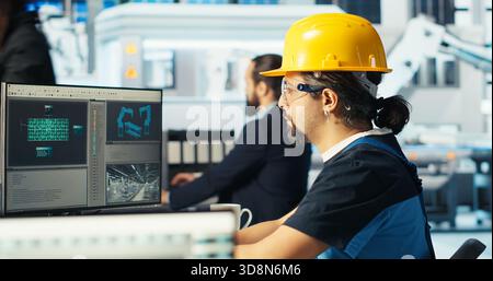 Photovoltaics factory manager shows engineer improvements to be made of robot arms manufacturing solar panels. Man shows technician upgrades needed after inspecting solar plant machinery, camera B Stock Photo