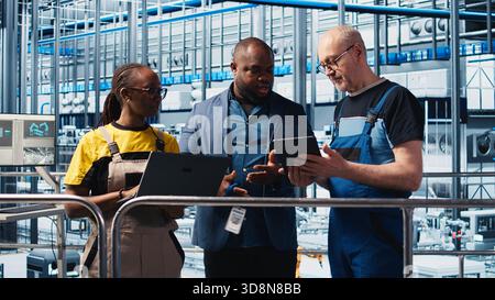 Supervisor overseeing work done by engineers in industry 4.0 solar panels plant to reduce downtime. Photovoltaics smart factory manager tasking workers with fixing damaged IoT sensors, camera A Stock Photo