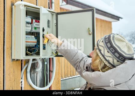 Examining open electrical cabinet homeowner observes breakers with meter placed by utility crew on wall of country dwelling. Stock Photo