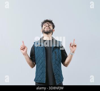 Handsome man in glasses pointing an advertising up isolated. Young man pointing blank space up and smiling Stock Photo