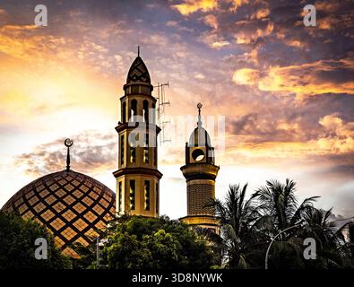 A mosque with two minarets against a dramatic sunset sky. Stock Photo