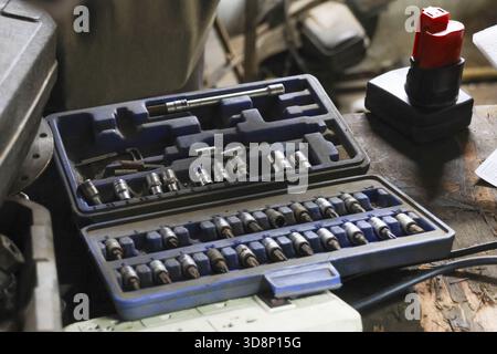 Open socket wrench set with various metal tools organized in case on workbench. This mechanic and repair equipment ready for DIY project or automotive Stock Photo
